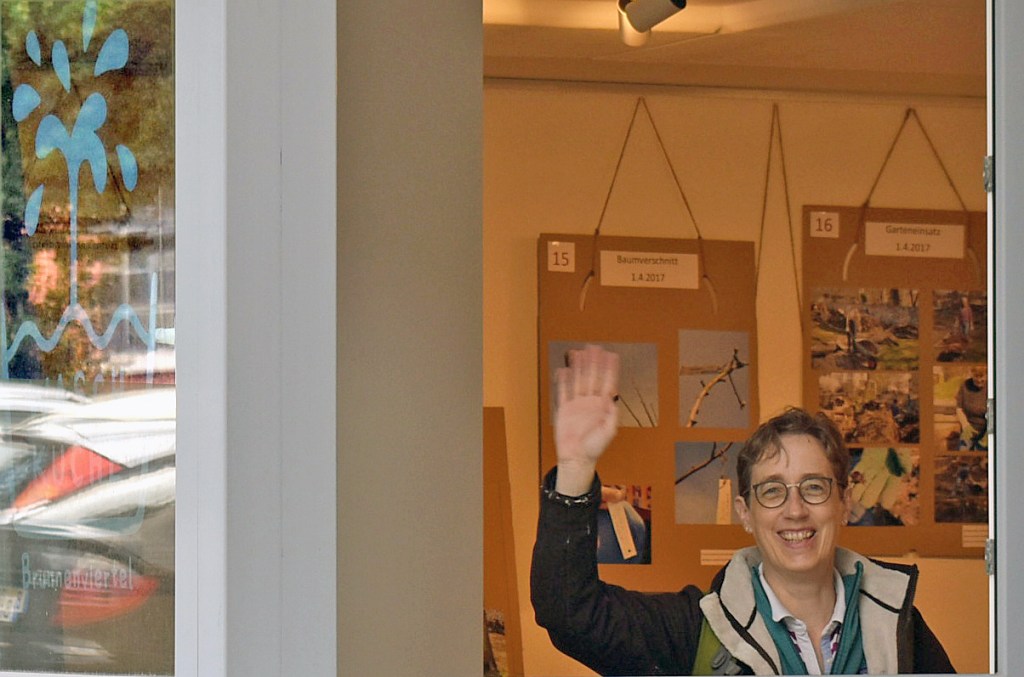 Gastgeberin Heike Mohaupt-Wonnemann winkt aus der Waschküche. Im Hintergrund sind einige Tafeln mit Fotos von Michael Becker zu sehen. Foto: Michael Becker