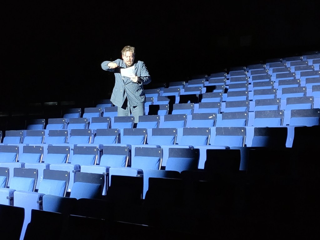 Frederic Böhle liest Franz Kafka - er sitzt dabei im Zuschauerraum, das Publikum auf der Bühne. Foto: Hensel