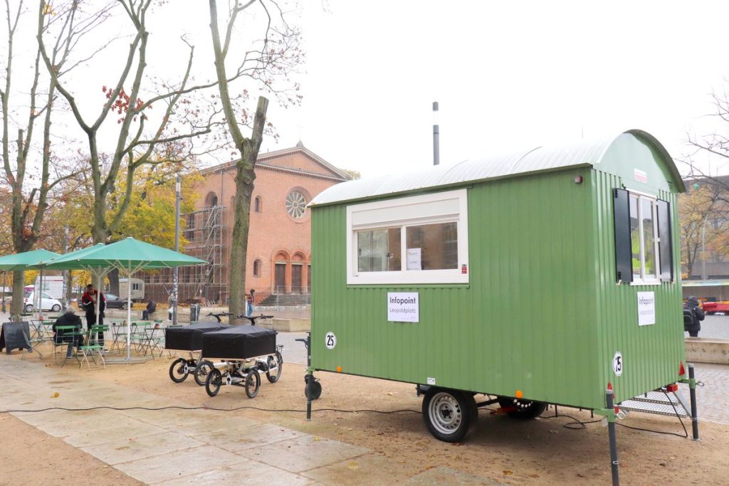 Infopoint im blattgrünen Bauwagen auf dem Leopoldplatz