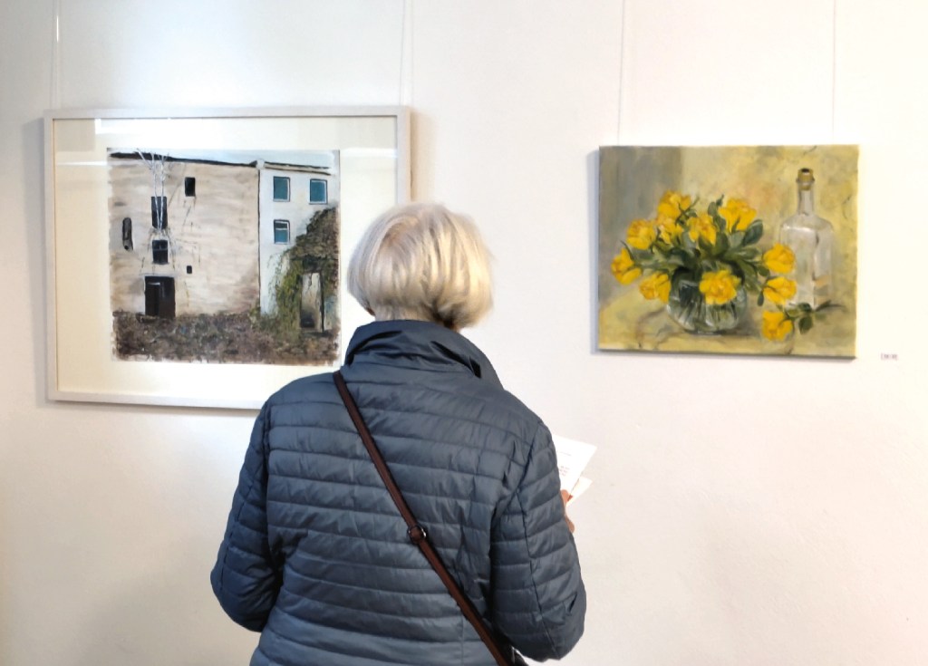 Eine Besucherin schaut sich zwei Bilder der Ausstellung an. Foto: Hensel
