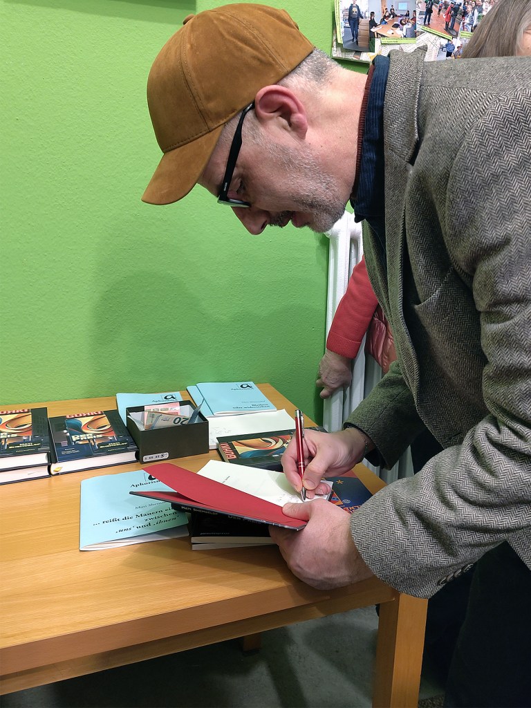 Der Autor signiert ein Buch. Foto: Hensel