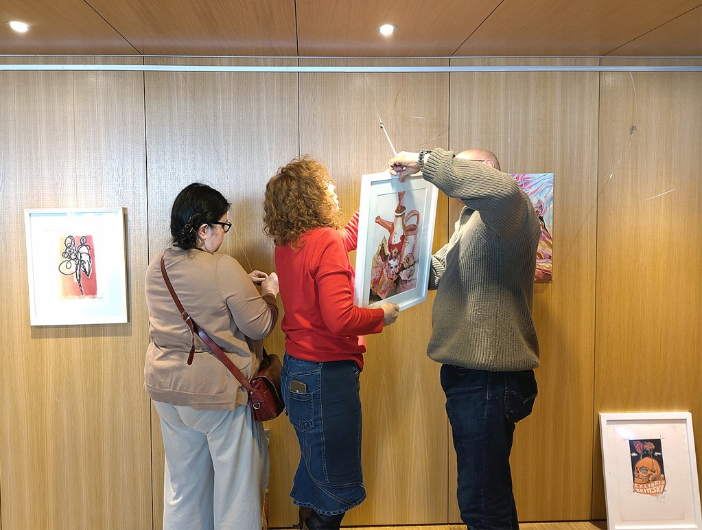 Gemeinsam werden die Bilder aufgehängt. Foto: Hensel