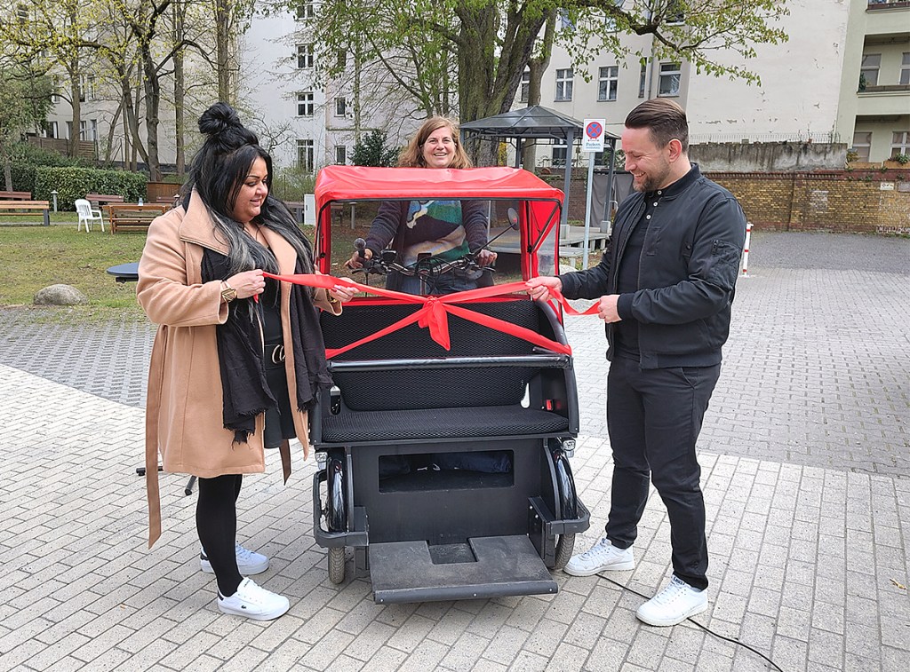 Die rote Schleife wird entfernt, die Rikscha ist fahrbereit. Dabei sind (von links): Stefanie Tepie Tame von PGS Soziales, Stefanie Brummer von fLotte Sozial und Stadtrat Christoph Keller. Foto: Hensel