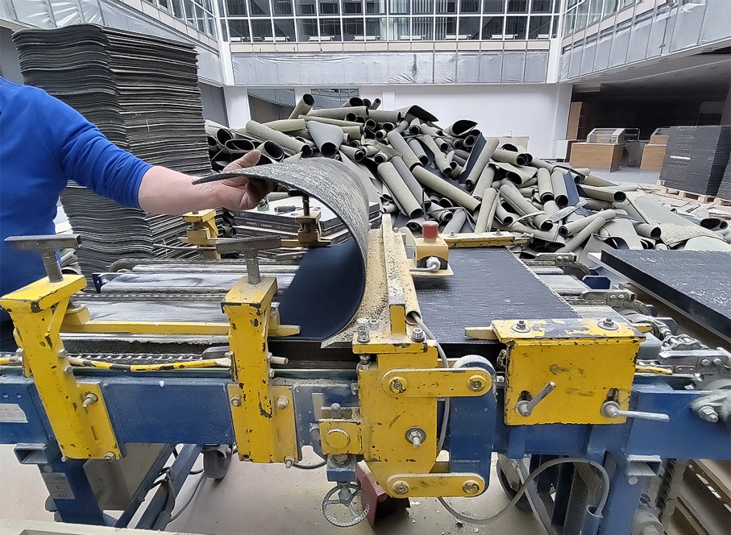 Eine Teppichfliese wird vom Untergrund getrennt. Foto: Hensel