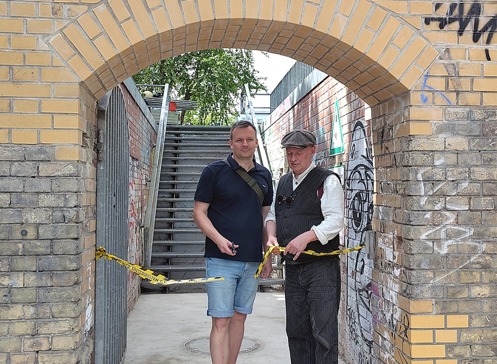 Dietmar Arnold von den Berliner Unterwelten (rechts) schneidet das symbolische Band durch und eröffnet den Zugang. Neben ihm: Ein Mitarbeiter der Bezirksamts. Foto: Hensel