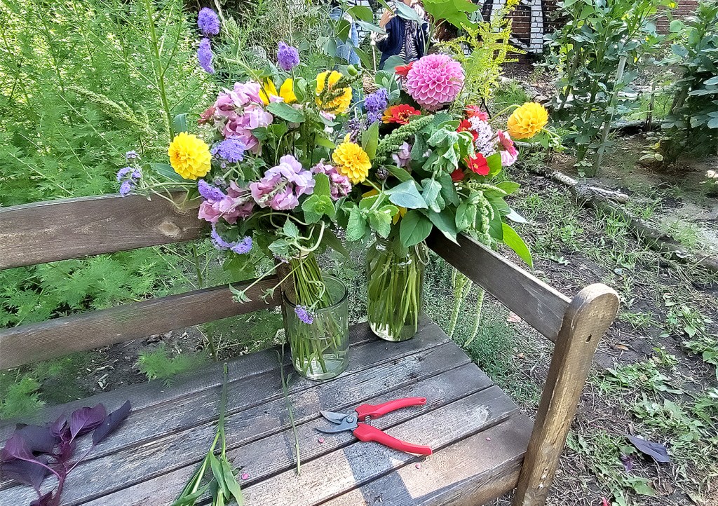 Zwei Blumensträuße auf einer Gartenbank