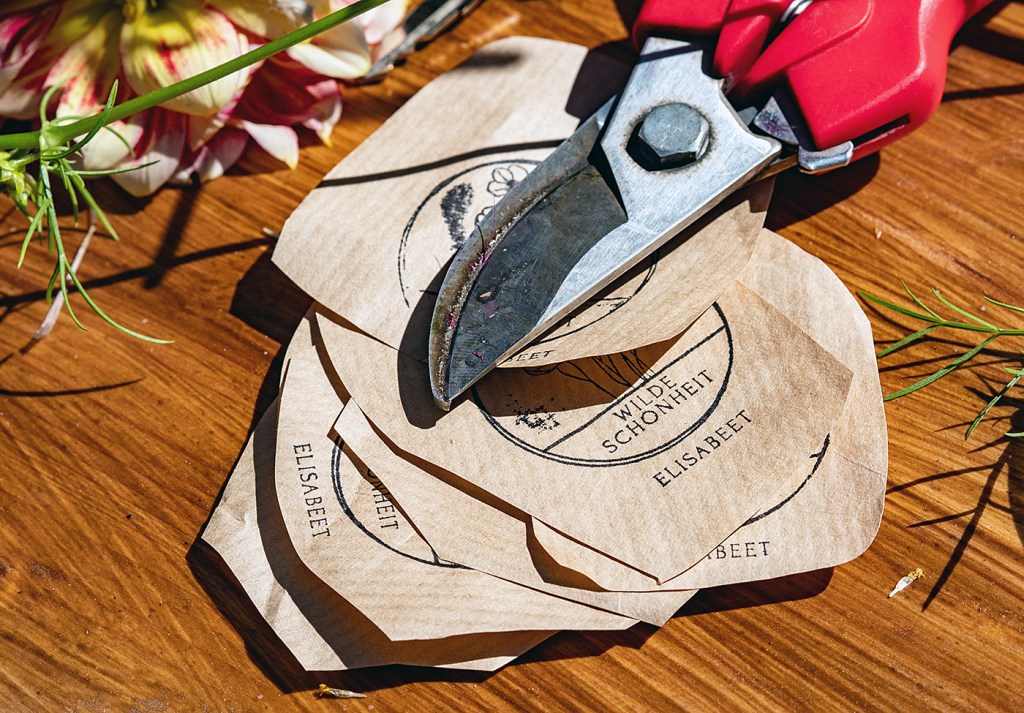 Gartenschere und Anhänger mit der Aufschrift „Wilde Schönheit“ liegen auf einem Tisch.