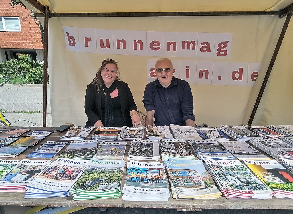 Zwei Mitglieder der Brunnenmagazin-Bürgerredaktion am Stand beim Kiezfest im Brunnenviertel 2026, daneben ältere Ausgaben des gedruckten Kiezmagazins