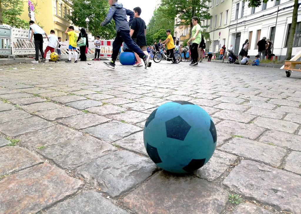Ball und spielende Kinder auf einer Spielstraße
