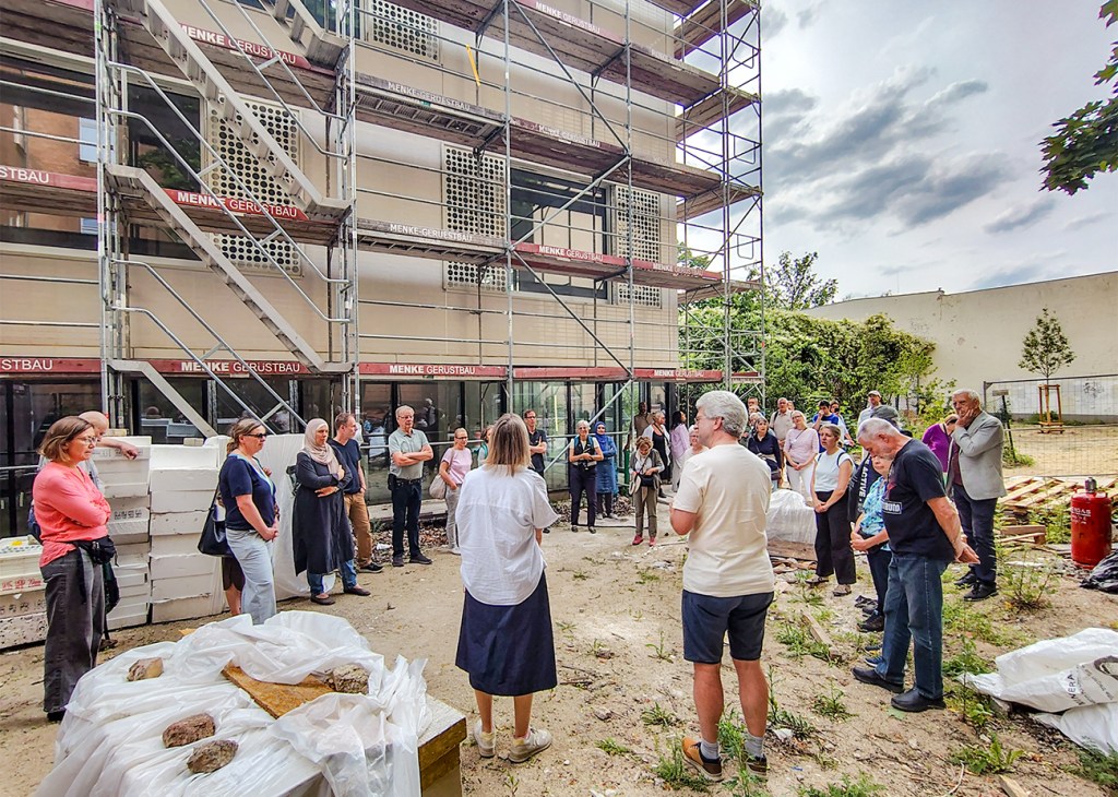 Besucherinnen und Besucher bei einer Baustellenführung vor dem Erweiterungsbau des Olof-Palme-Zentrums im Brunnenviertel.